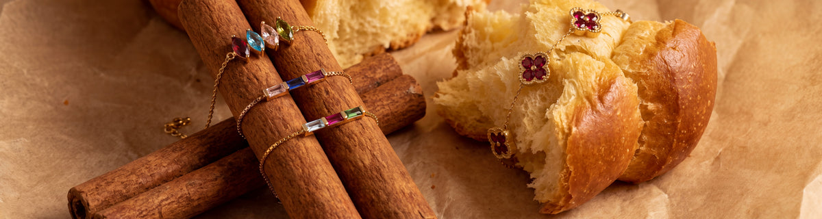 Dainty gold birthstone bracelets wrapped around cinnamon sticks and brioche