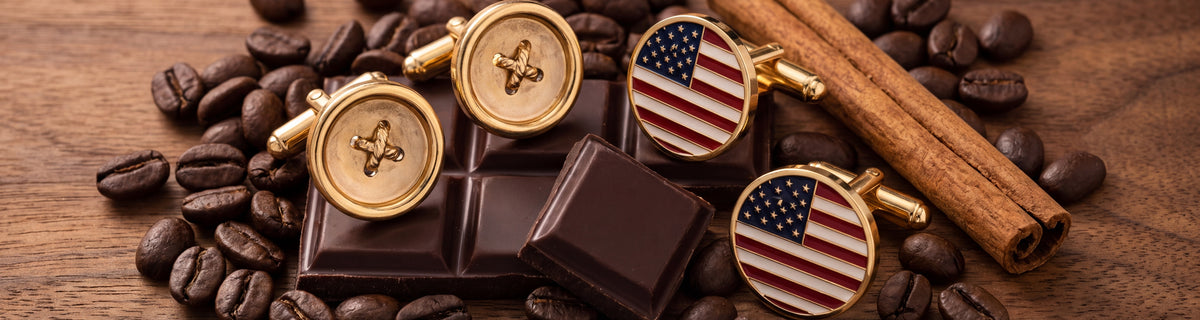 Gold sewing button and American flag cufflinks among coffee beans, dark chocolate and cinnamon