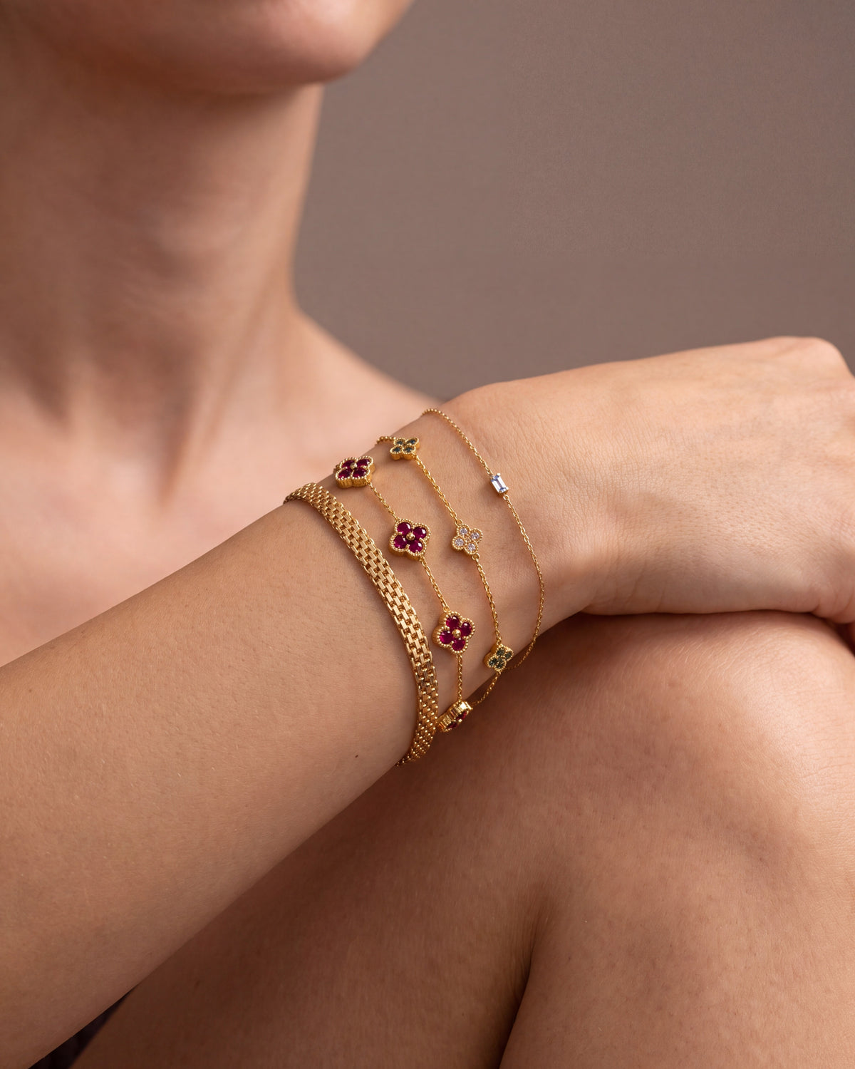 Stack of dainty gold birthstone bracelets on a wrist