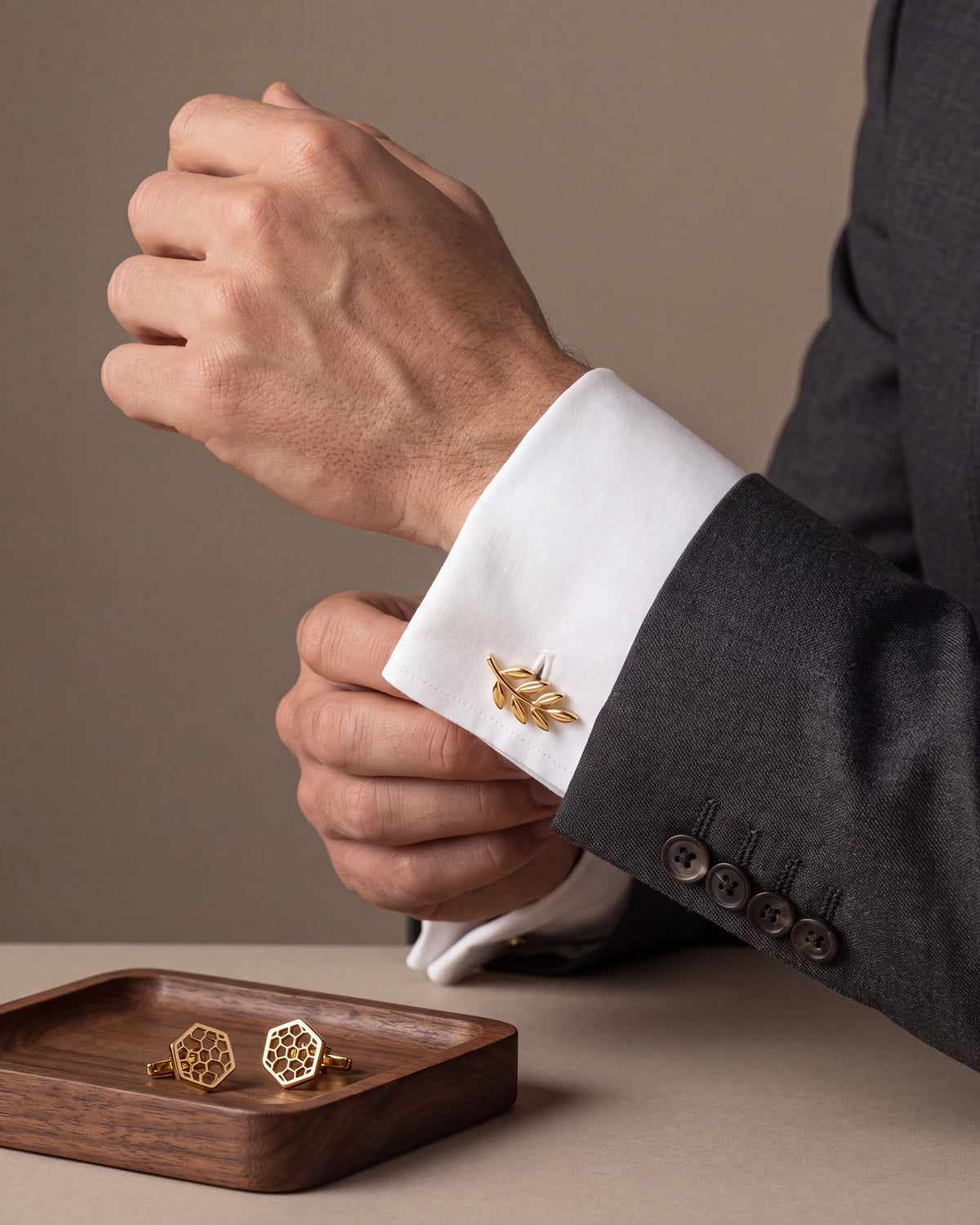 Gold olive branch cufflinks on a French cuff with honeycomb cufflinks on a walnut tray
