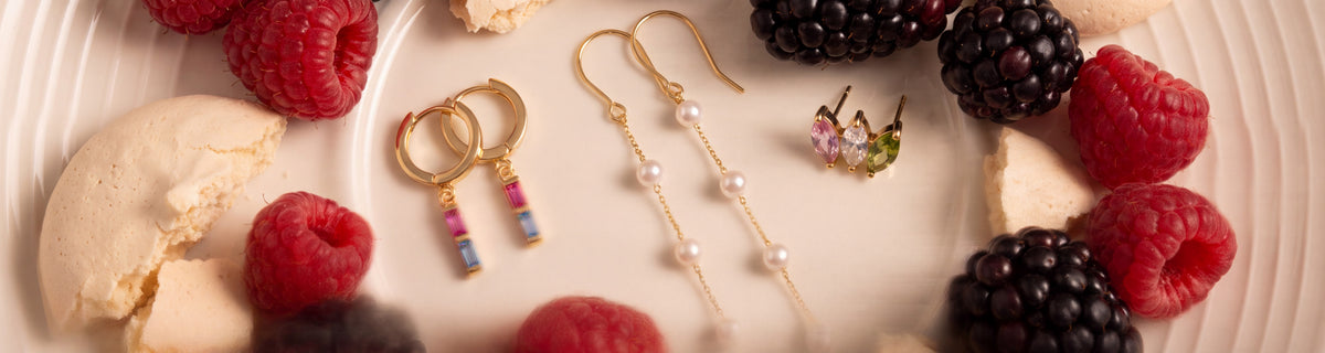 Gold pearl and birthstone earrings among berries and meringue