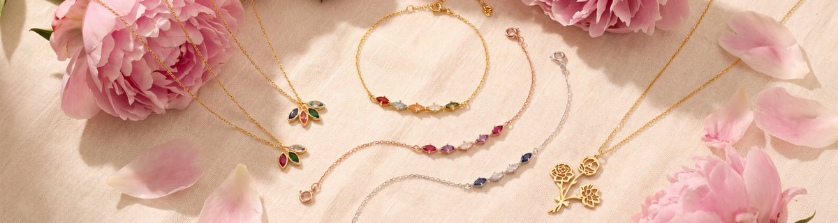 Leaf birthstone and birth flower jewelry among pink peonies