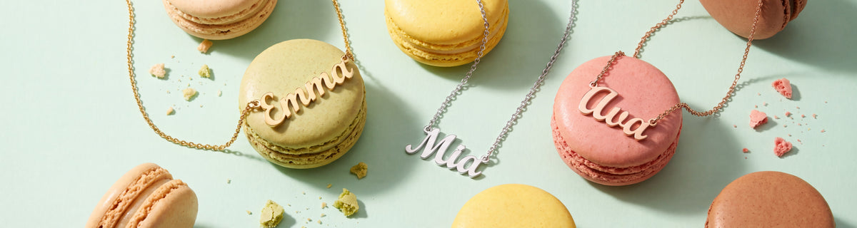 Gold, silver and rose gold name necklaces reading Emma, Mia and Ava with pastel macarons