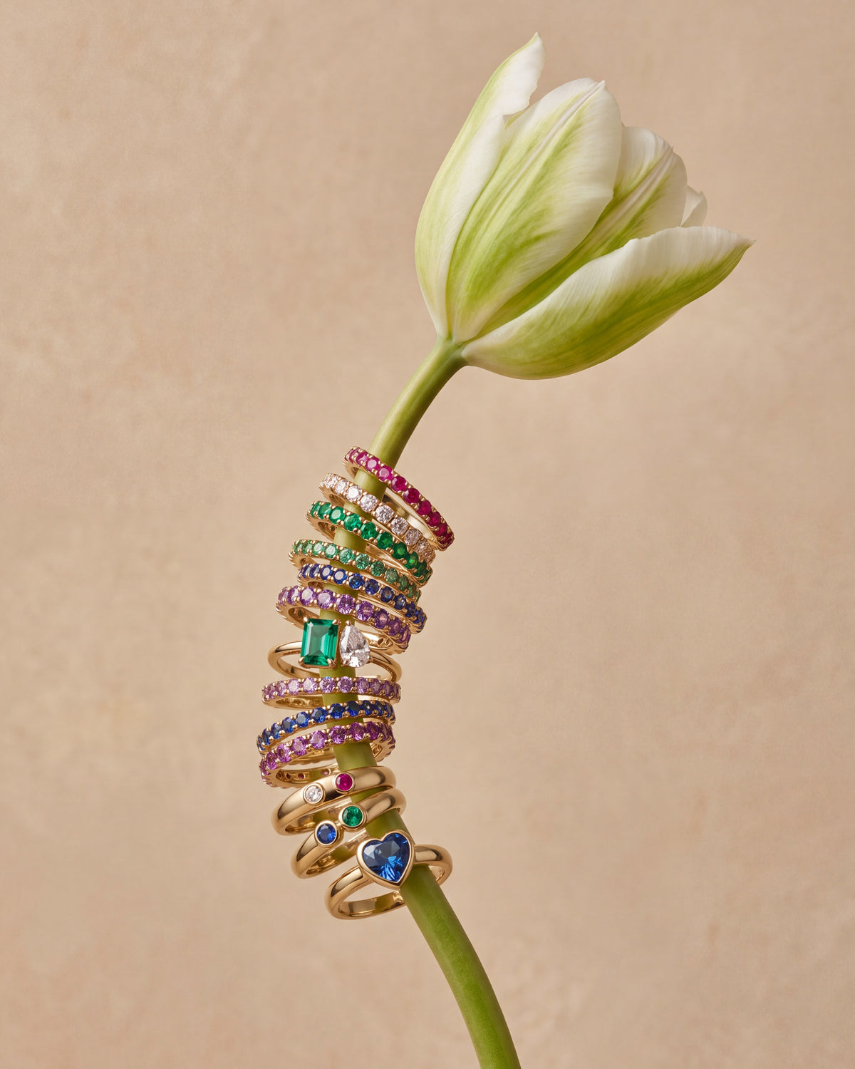 Gold birthstone rings stacked on a tulip stem